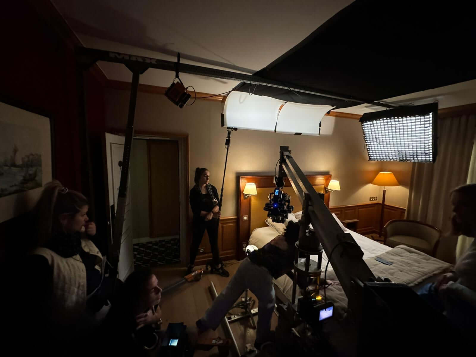 Behind-the-scenes of a film set featuring lighting and crew in a hotel room.