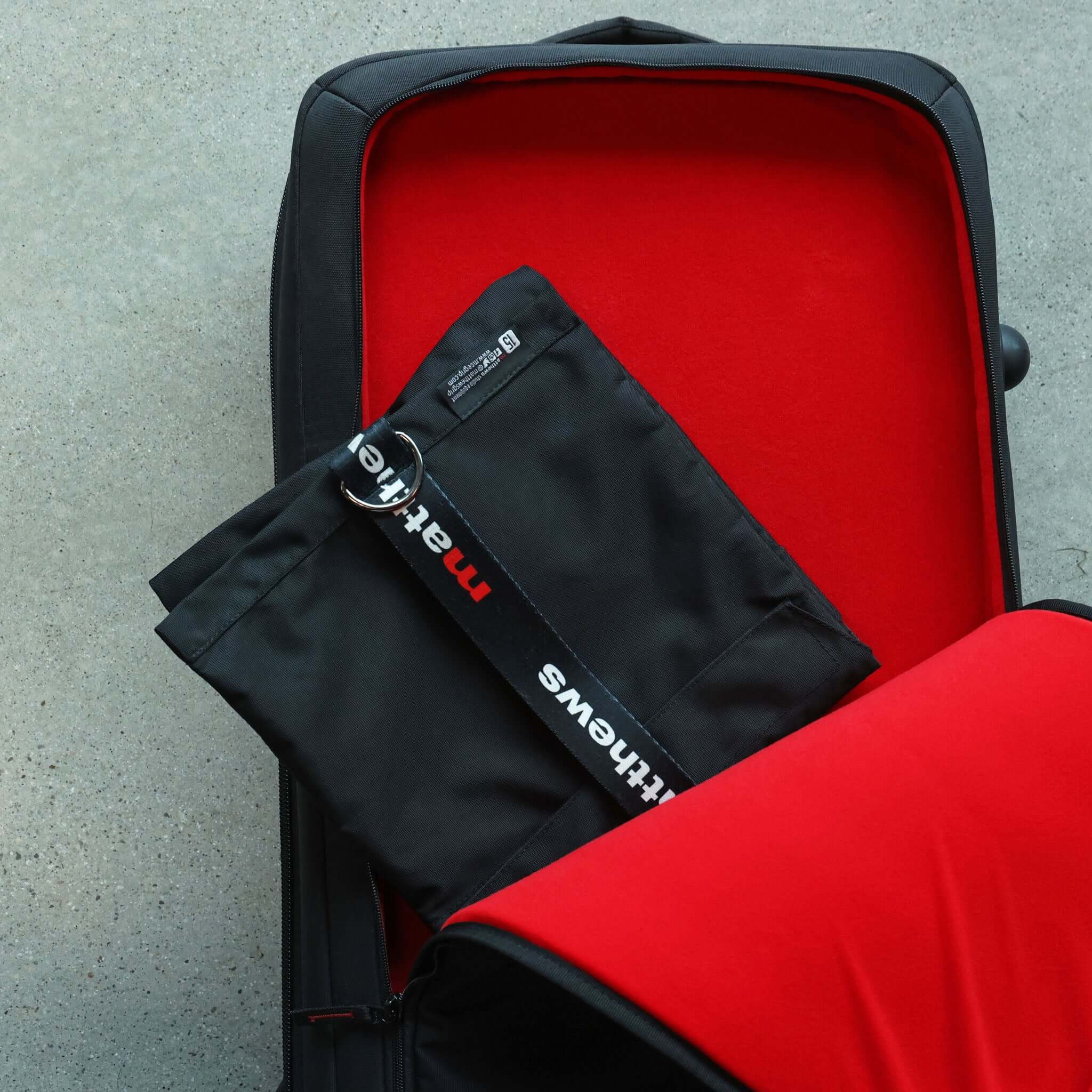 black travel bag placed inside an open red suitcase, showcasing travel essentials and organization.