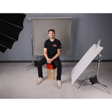 Man sitting on Apple Box with Apple Box Topper™ in a photography studio setup.