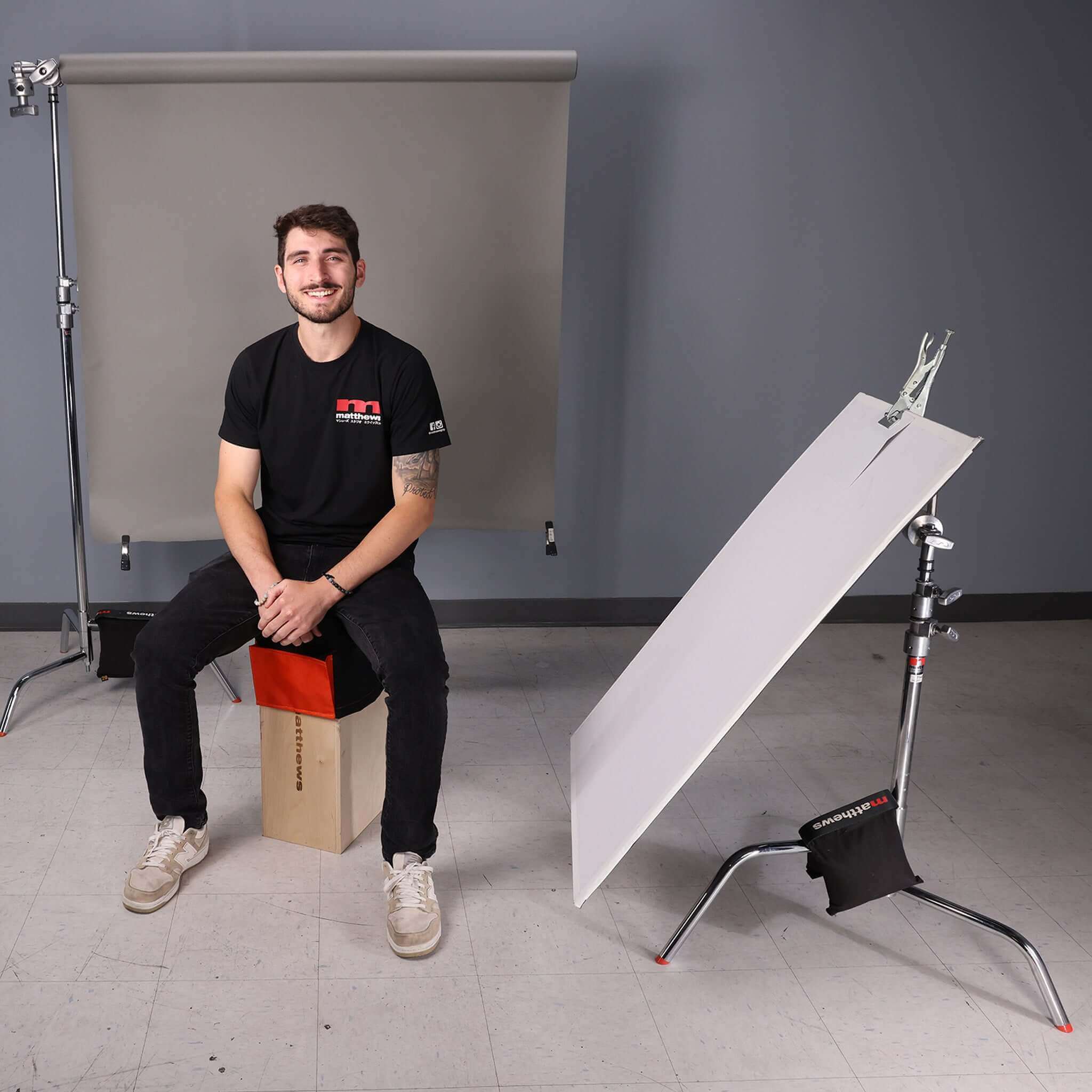 Person sitting comfortably on Apple Box with Apple Box Topper in a photography studio setting.