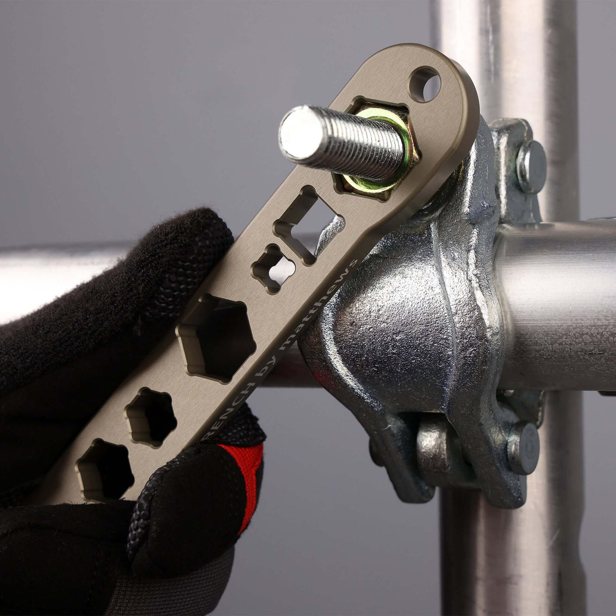 Close-up of the Patriot Wrench adjusting a clamp on a pipe, showcasing its versatile cutouts and ergonomic design.