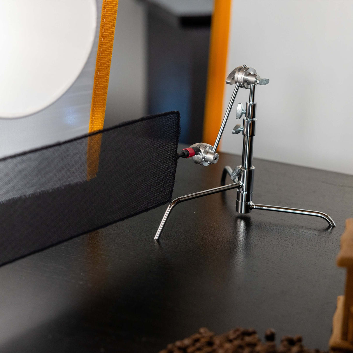 Matthews 5" Pocket C-Stand supporting a black fabric backdrop on a tabletop, ideal for product photography.