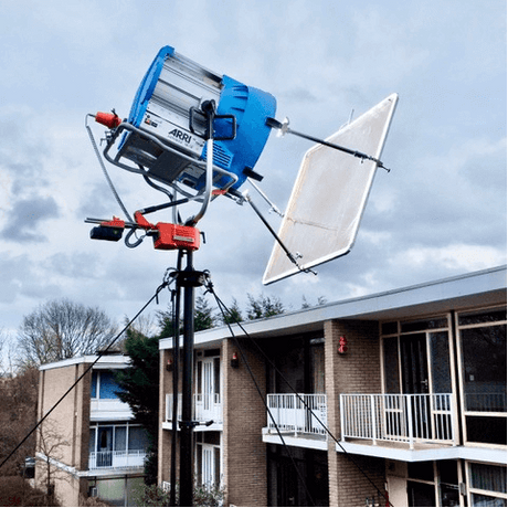 LITEMOVER universal remote head controlling large industry-specific light and reflector board setup on a sturdy tripod outdoors.